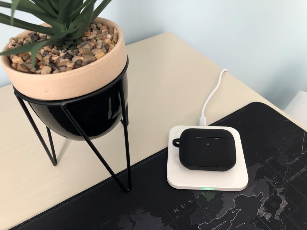 AirPods Pros on a wireless charger next to a plant ornament